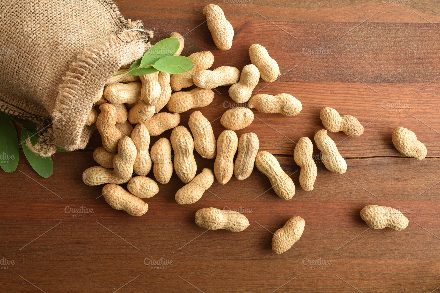 Cloth sack filled with peanuts scattered on rustic wooden table, a Food & Drink Photo by Davizro's Market