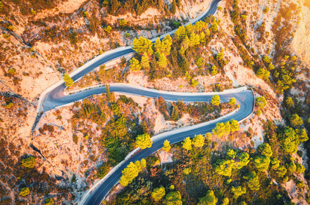 Aerial view of winding road in beautiful mountains at sunset, a Transportation Photo by den-belitsky