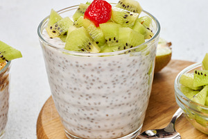 Yogurt and chia seed pudding in a glass, kiwi pieces. White tabl, a Food & Drink Photo by ndanko
