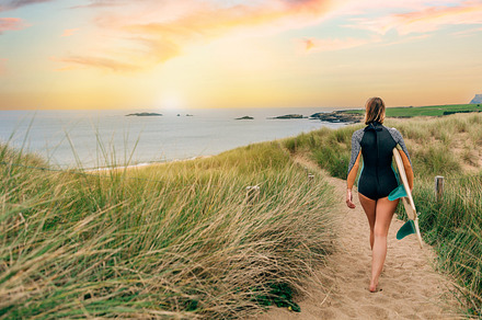 Surfer woman with wetsuit and surfboard walking along the path between the dune, a Holiday Photo by davidpereiras