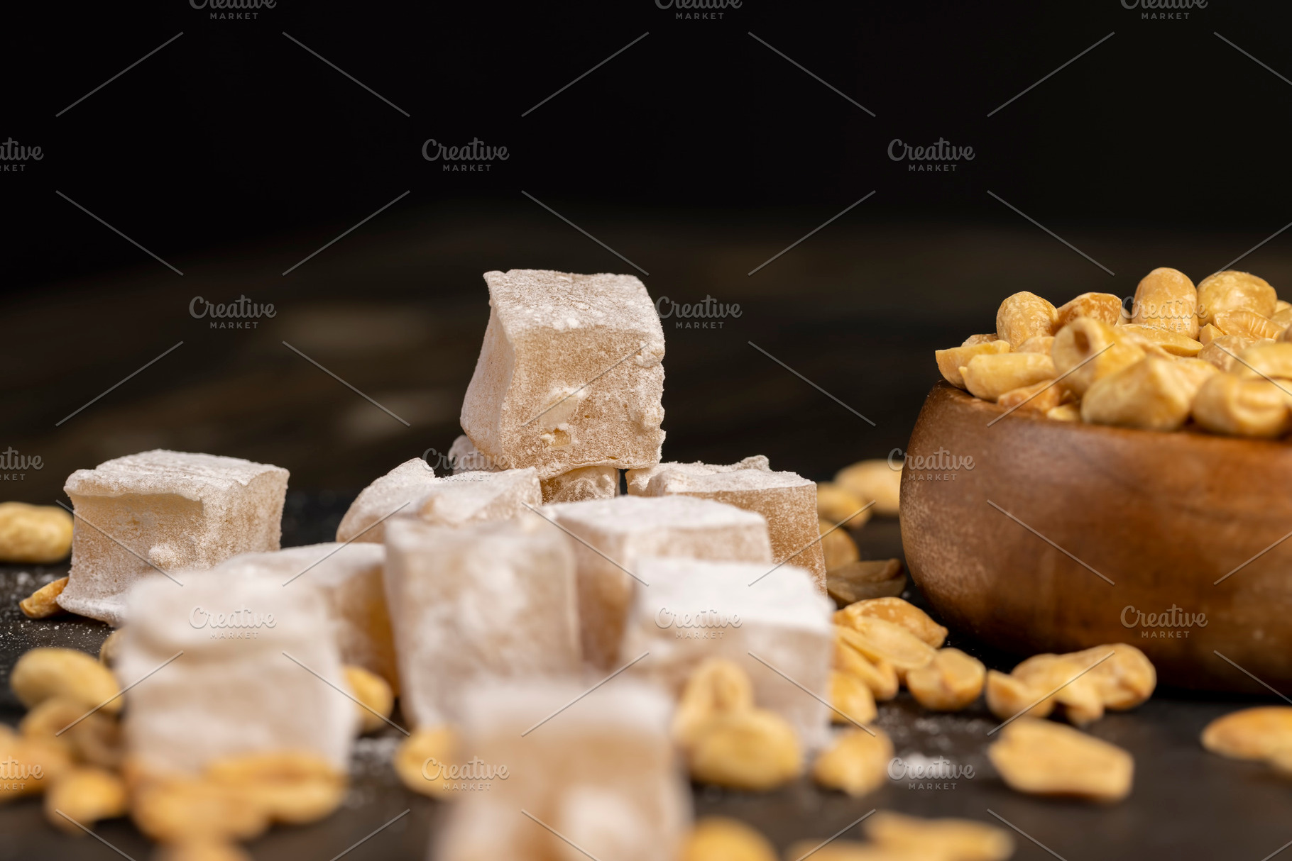 Turkish delight and toasted peanuts on a black slate surface, close up, a Photo by rsoollAI