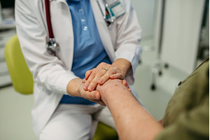 Caring doctor holding senior patient, a Health & Medical Photo by HalfPoint