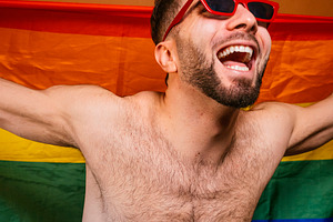 Happy man celebrating pride with rainbow flag, a Photo by karrastock