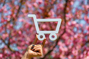 Hand holding a white shopping cart cutout with a backdrop of vib, a Nature Photo by Ales Munt