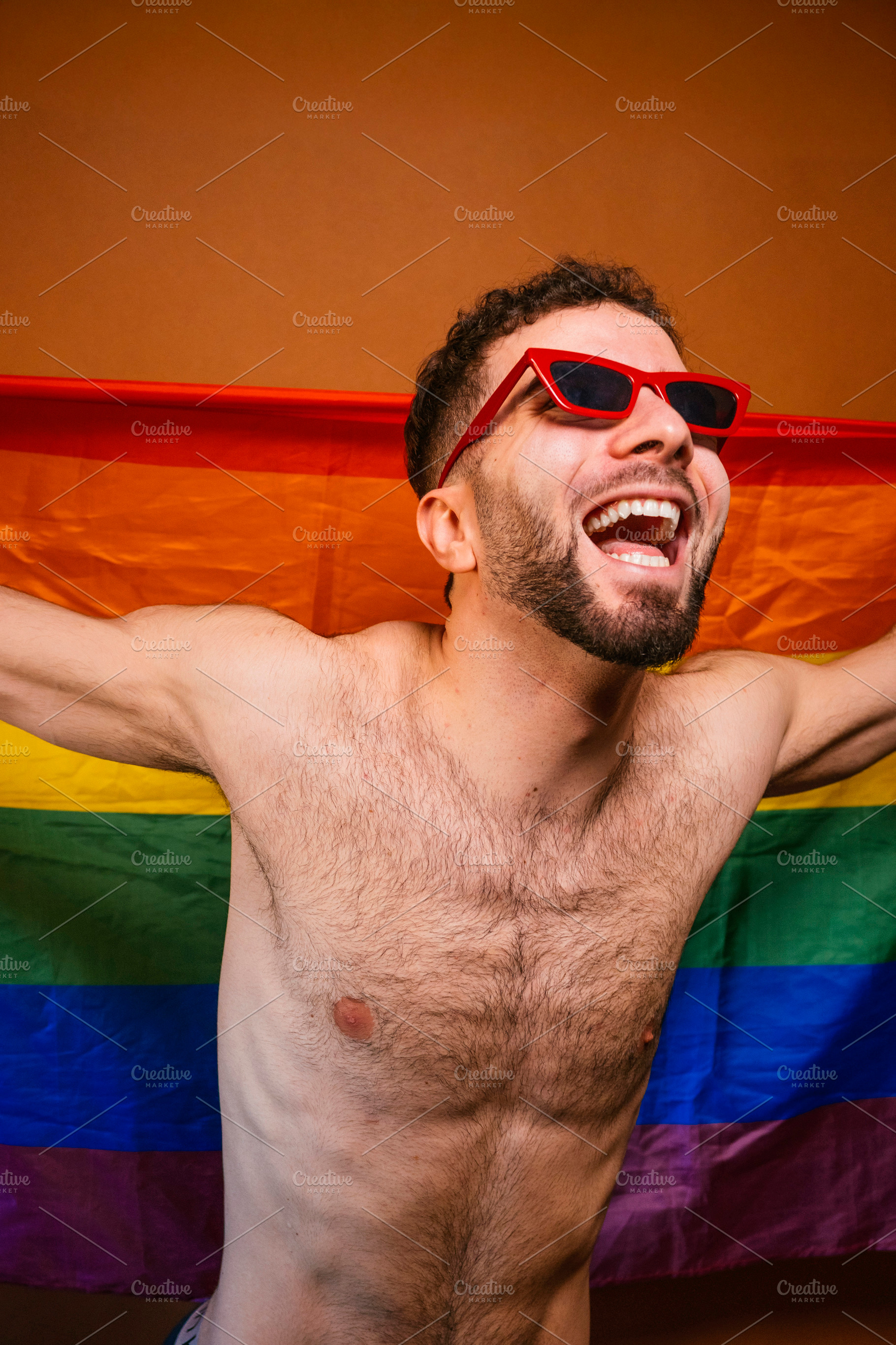 Happy man celebrating pride with rainbow flag, a Photo by karrastock