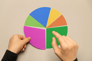 Hand selecting a segment on a colorful pie chart representing da, a Photo by salmon.black