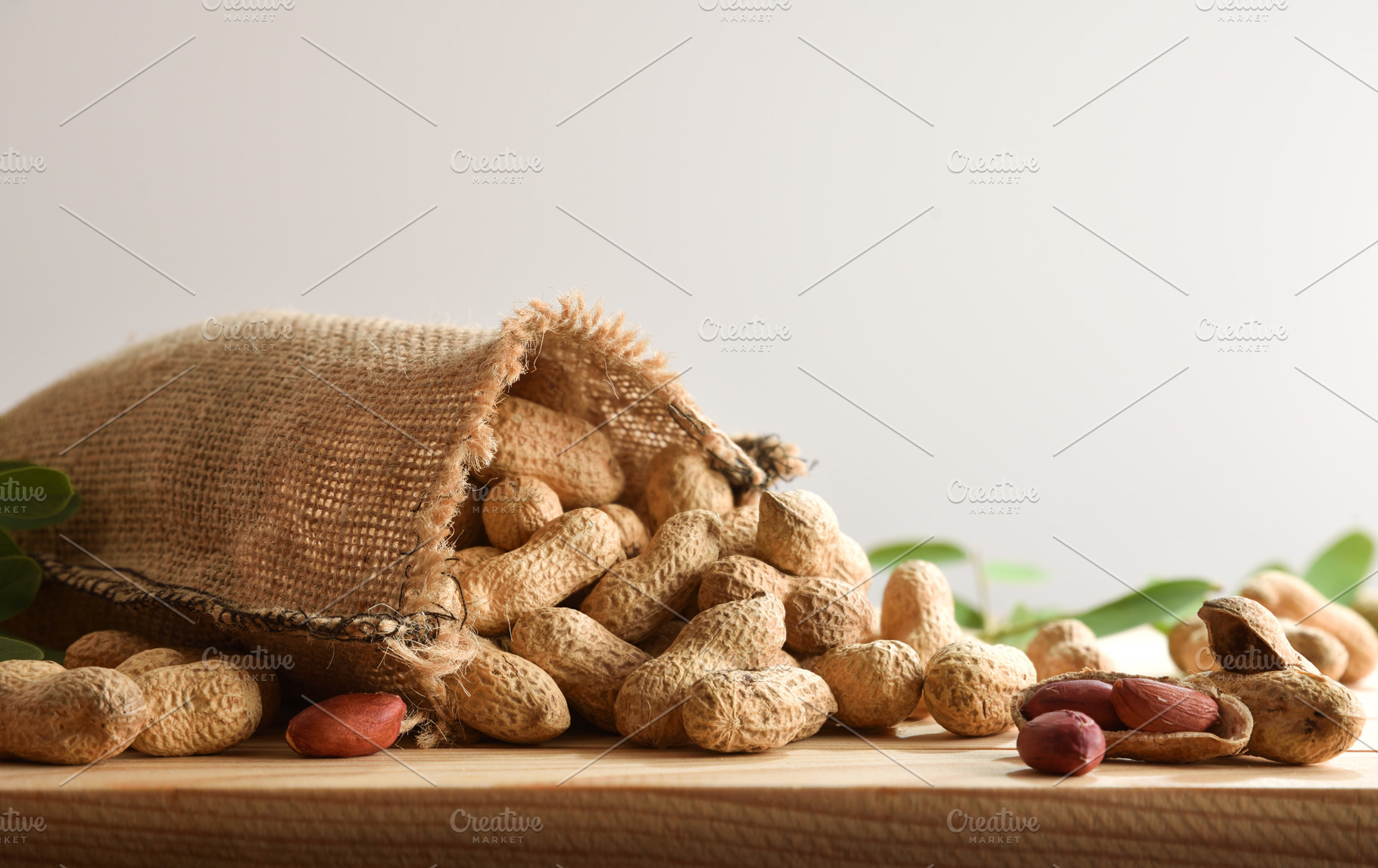 Cloth sack filled with peanuts scattered on table isolated backg, a Food & Drink Photo by Davizro's Market