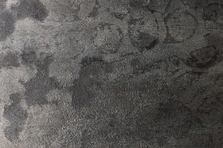 Close up of a worn and scratched metal surface with dark and lig