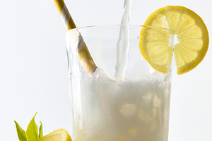 Filling glass with lemon soda decorated with straw and lemon, a Food & Drink Photo by Davizro's Market