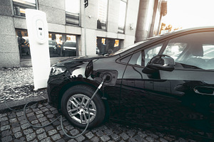 Electric car charging on city street, a Transportation Photo by SkyNext