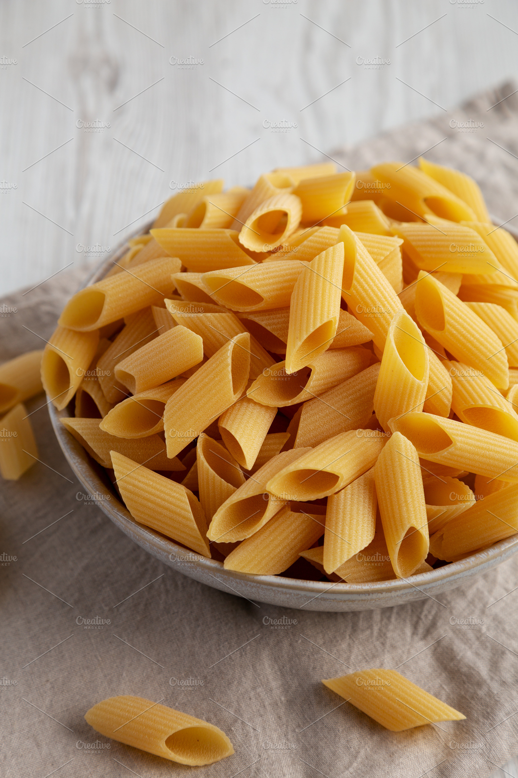 Raw Organic Dry Pennoni Pasta in a Bowl, side view., a Food & Drink Photo by LiudmylaChuhunova