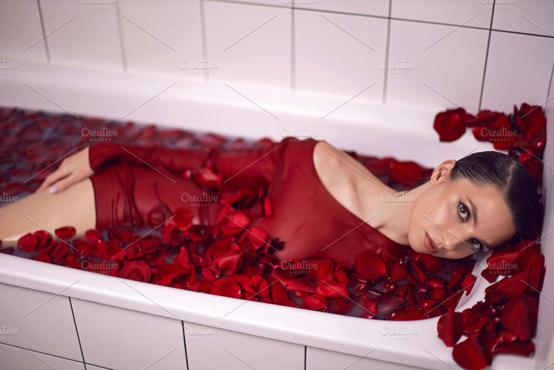 portrait of a beautiful sexy woman in a red dress lies in a white bathroom with, a Person Photo by SaulichPhoto