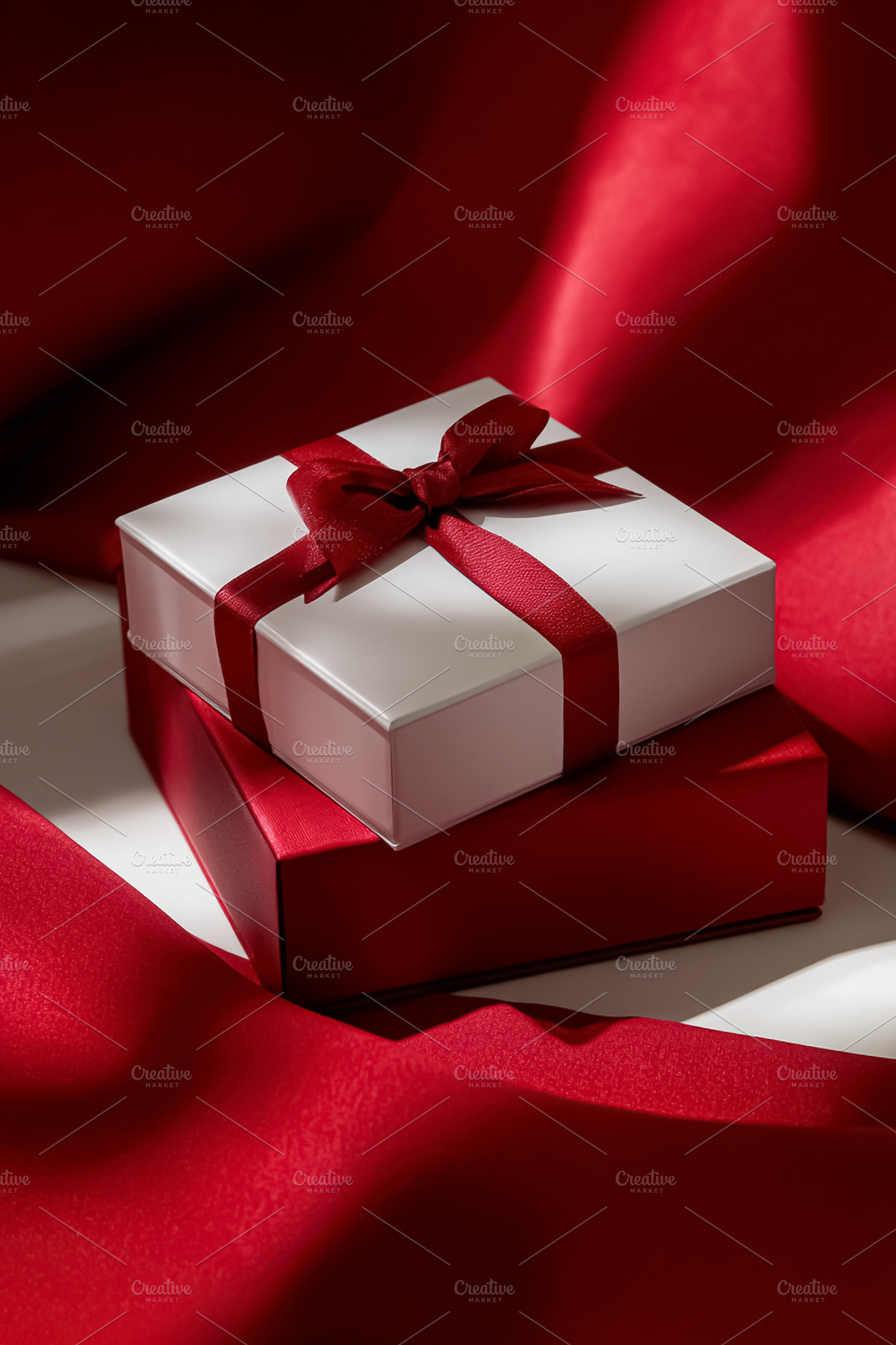 White gift box with red ribbon and bow on red background, repres, a Photo by Studio ANNA