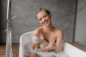 Happy lady sitting in hot bubble bath, looking and smiling at camera, enjoying, a Photo by Prostock-Studio