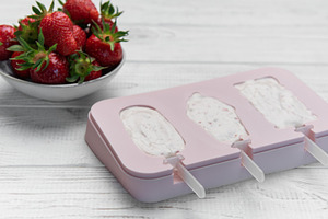 Preparing homemade strawberry yogurt popsicles on wooden backgro, a Food & Drink Photo by Olena Rudo