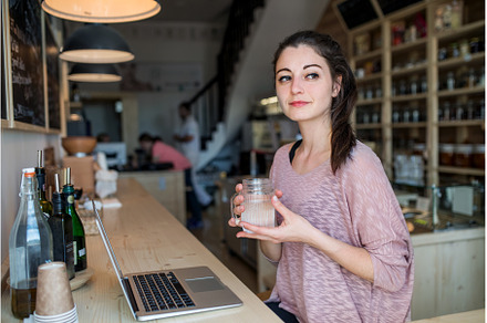 Beautiful woman working remotely in, a Food & Drink Photo by HalfPoint