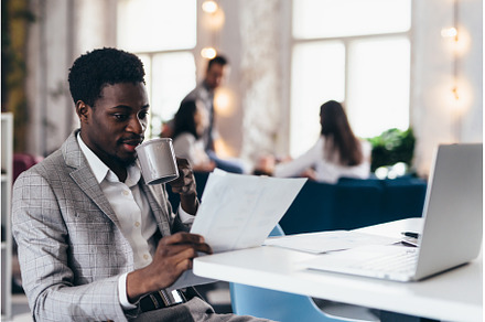 Young black man using laptop in, a Business Photo by undrey