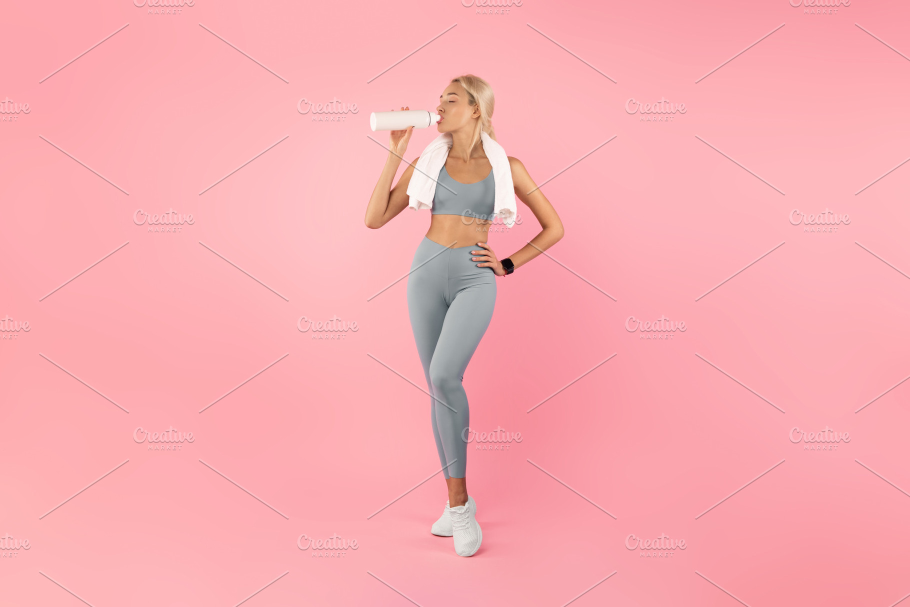 Sporty woman drinking water from bottle after exercising, a Photo by Prostock-Studio