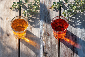Comparison of two glass cups with liquid under different lighting on a wooden t, a Food & Drink Photo by AlyaAnd
