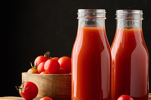 Full glass bottle with tomato juice on dark background, a Food & Drink Photo by ndanko