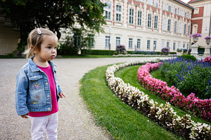Little girl exploring a colorful garden in Lancut, Poland during springtime, a Photo by AS photostudio