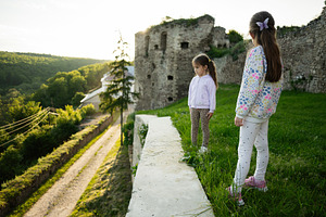 Two girls exploring an old castle with scenic nature views at sunset, a Person Photo by AS photostudio