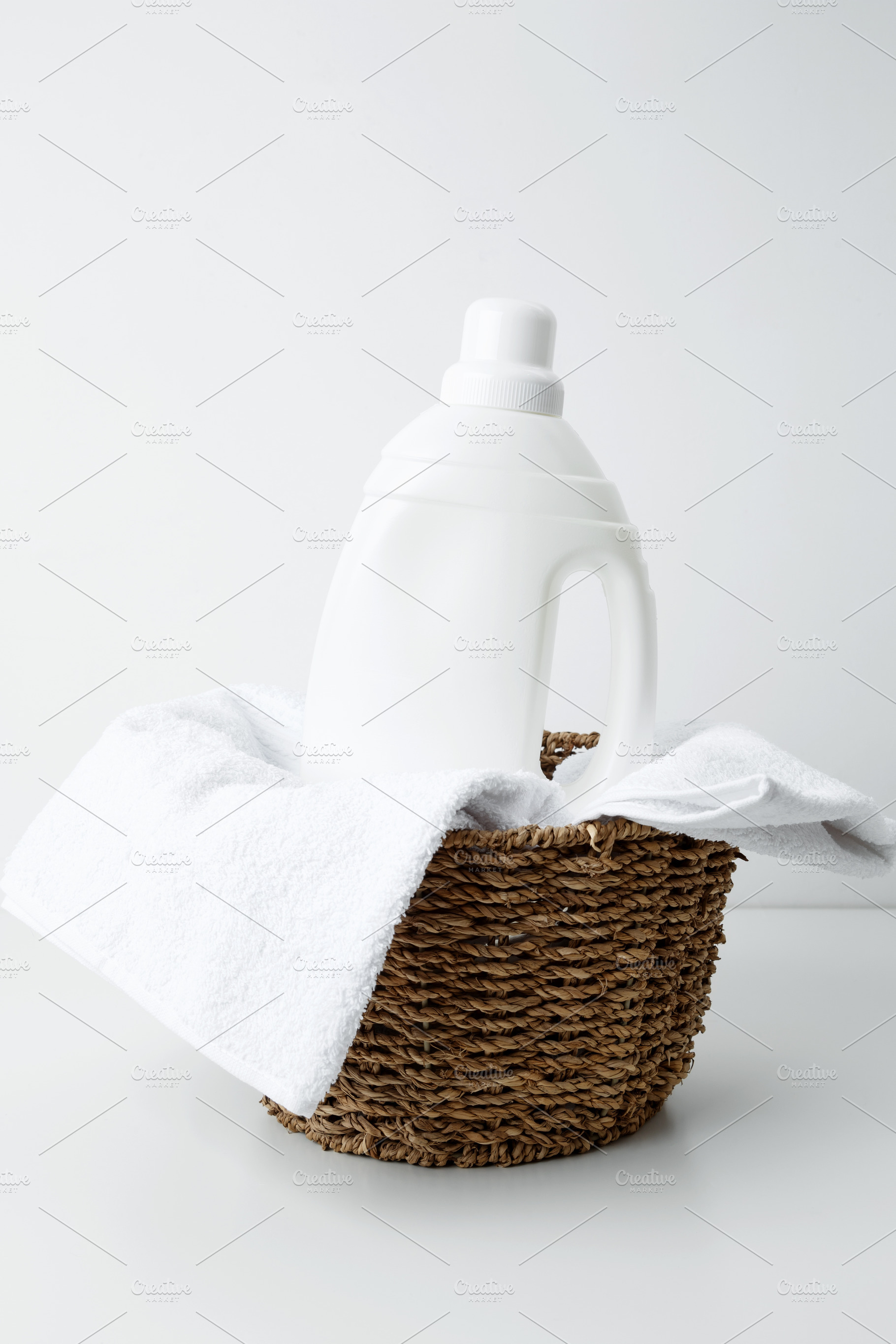 Laundry detergent branding mock up and basket filled with clean white towels. H, a Photo by matucha