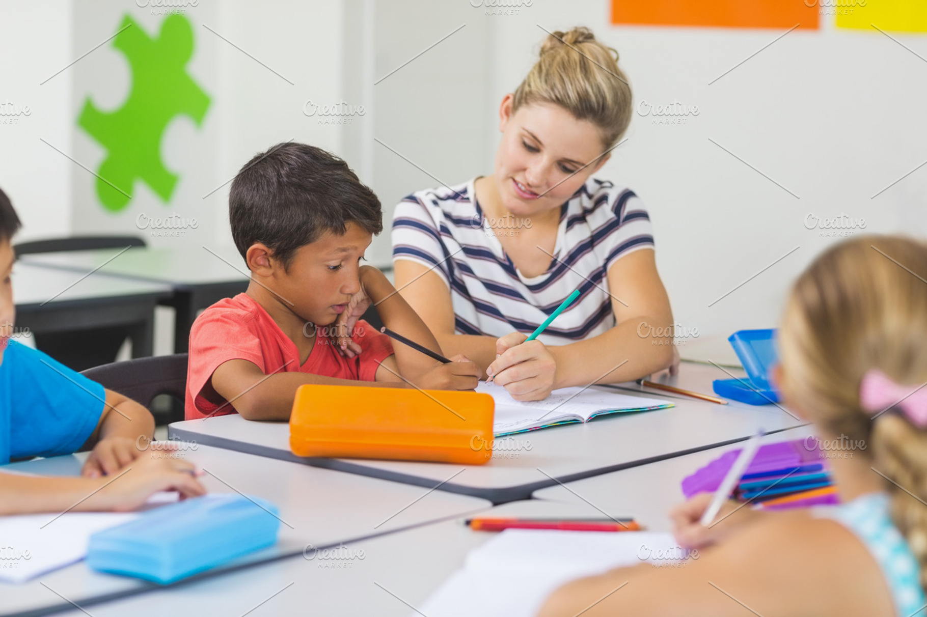 Teacher helping kids with their homework in classroom, a Photo by wavebreak