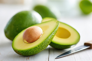 Fresh halved avocado with seed on wooden table, a Food & Drink Photo by AlyaAnd