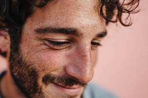 Smiling young man with beard on peach background, a Person Photo by AlyaAnd