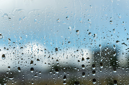Raindrops on a window with a blue cloudy sky in the background., an Abstract Photo by Eugene_Photo