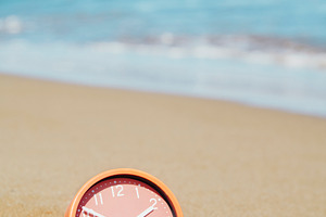 a clock rests in the sand at an empty beach, a Photo by Nito