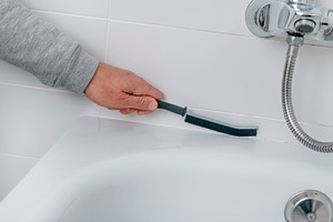 a man cleans the bathtub tile grout, a Photo by Nito
