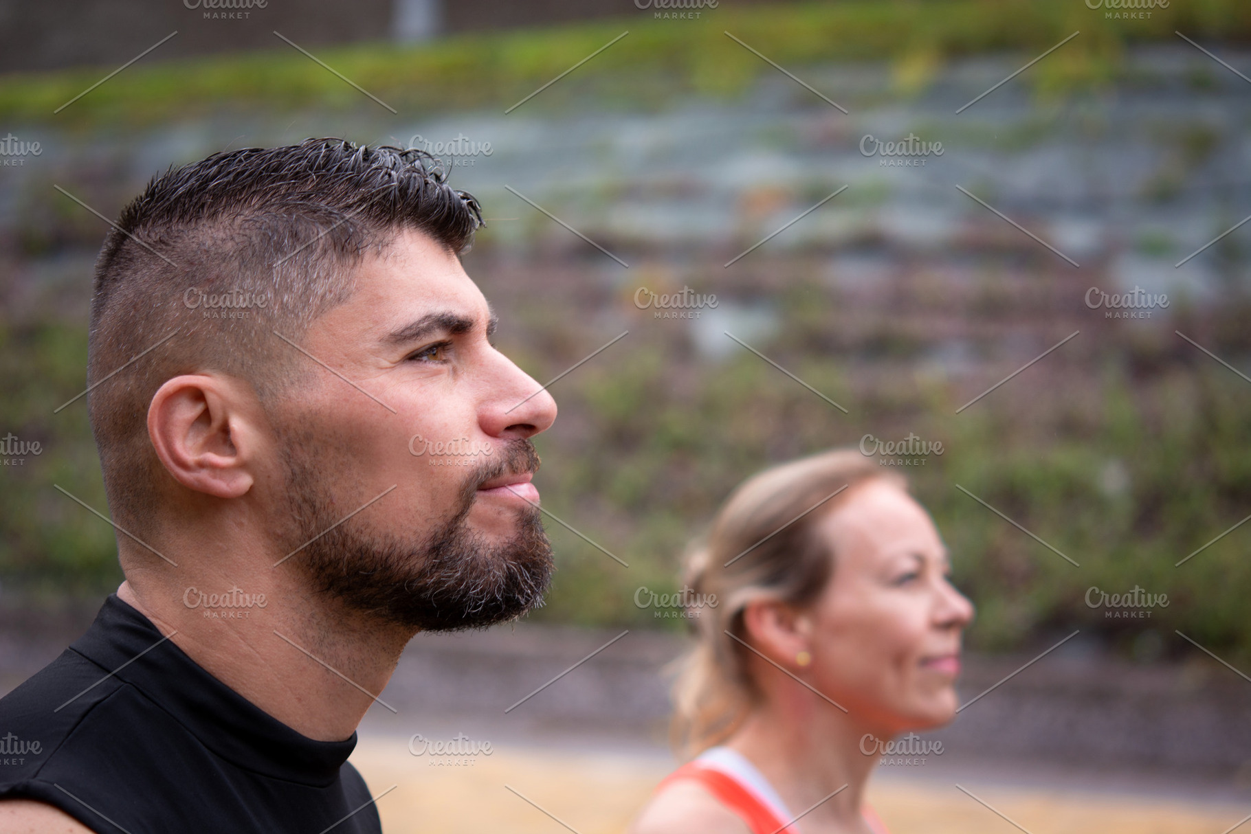 Active couple standing outdoors, woman in foreground looking ahead with focus, a Sports & Recreation Photo by etorres69
