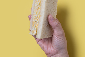 Hand holding a tamago Sando sandwich, a Photo by etorres69