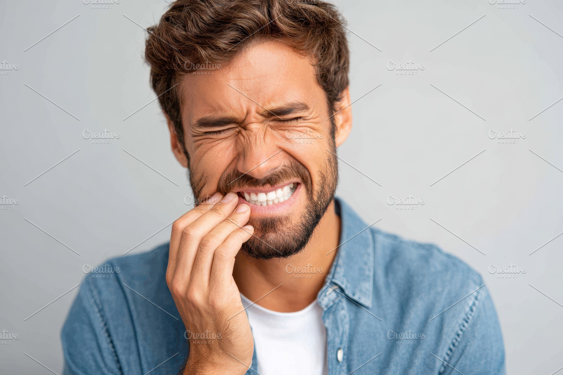 Middle-aged man with hand on cheek in pain because of a toothache, a Health & Medical Photo by AlyaAnd