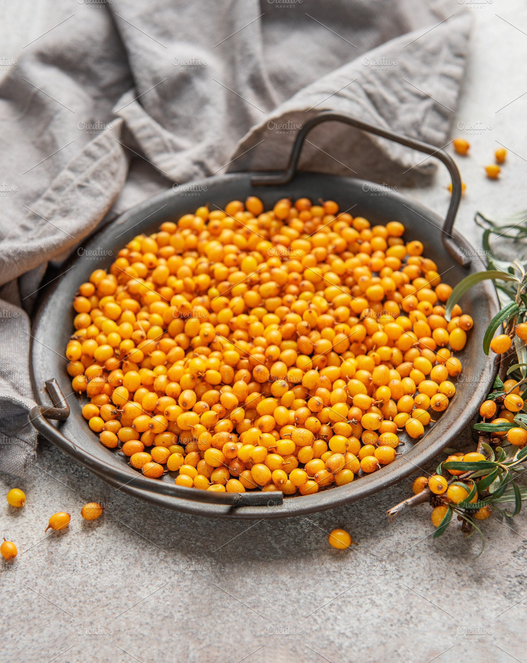 Fresh sea buckthorn berries filling a metal tray on a textured s, a Food & Drink Photo by Olena Rudo