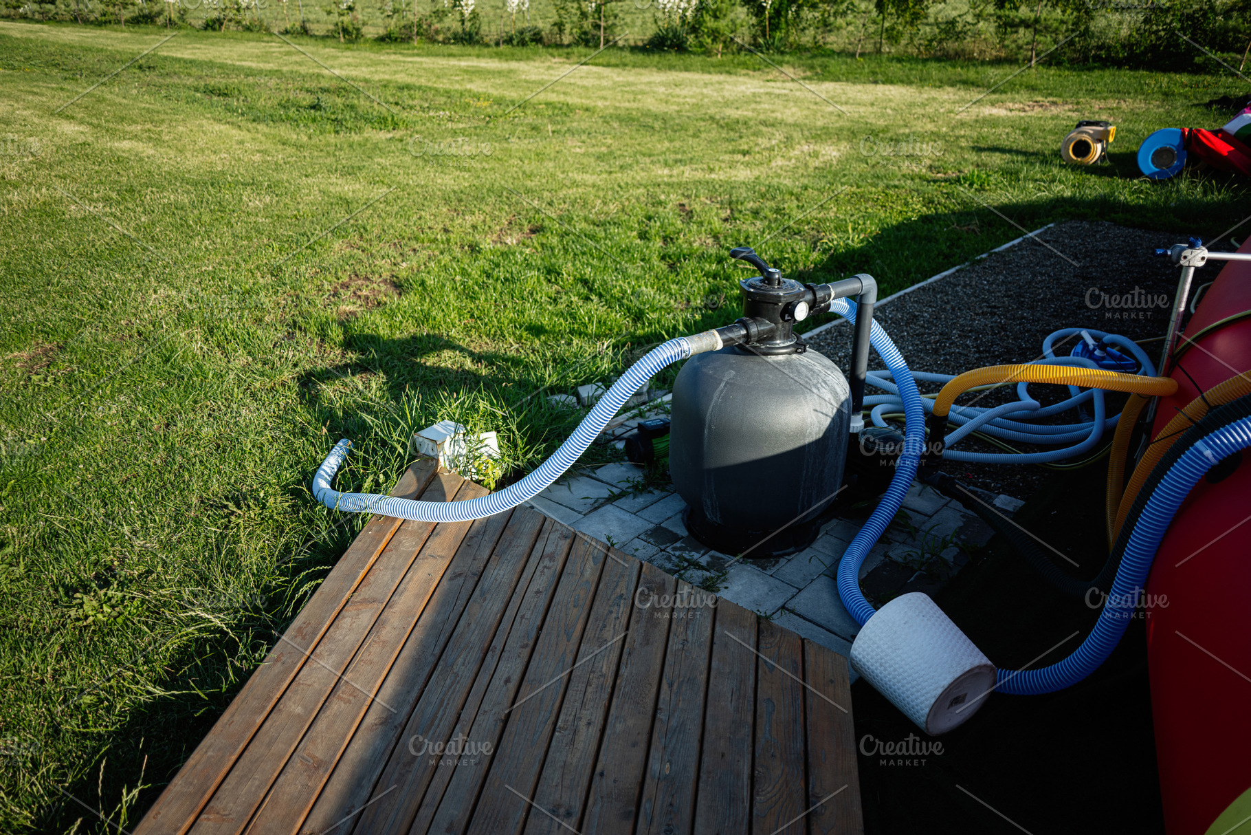 Pool equipment setup in grassy yard with pipes and filtration system outdoors, a Photo by AS photostudio