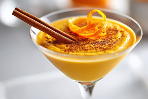 Delicious creamy mango cocktail garnished with cinnamon and orange peel in a st, a Photo by AlyaAnd