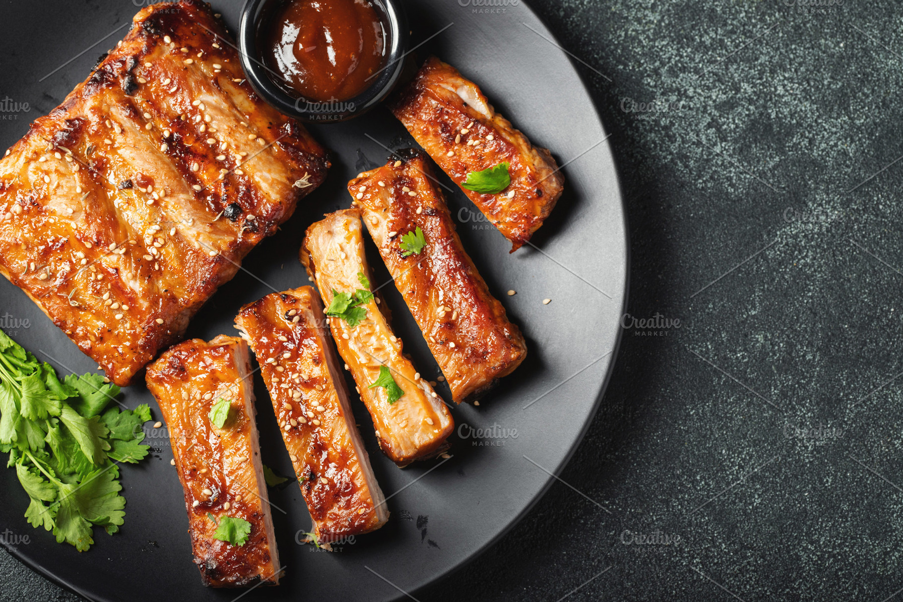 Hot grilled spare ribs from a summer BBQ served on a plate with sauce. Top view, a Food & Drink Photo by Budarinphoto