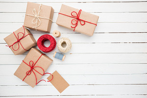 Homemade wrapped rustic brown paper packages on white wooden surface