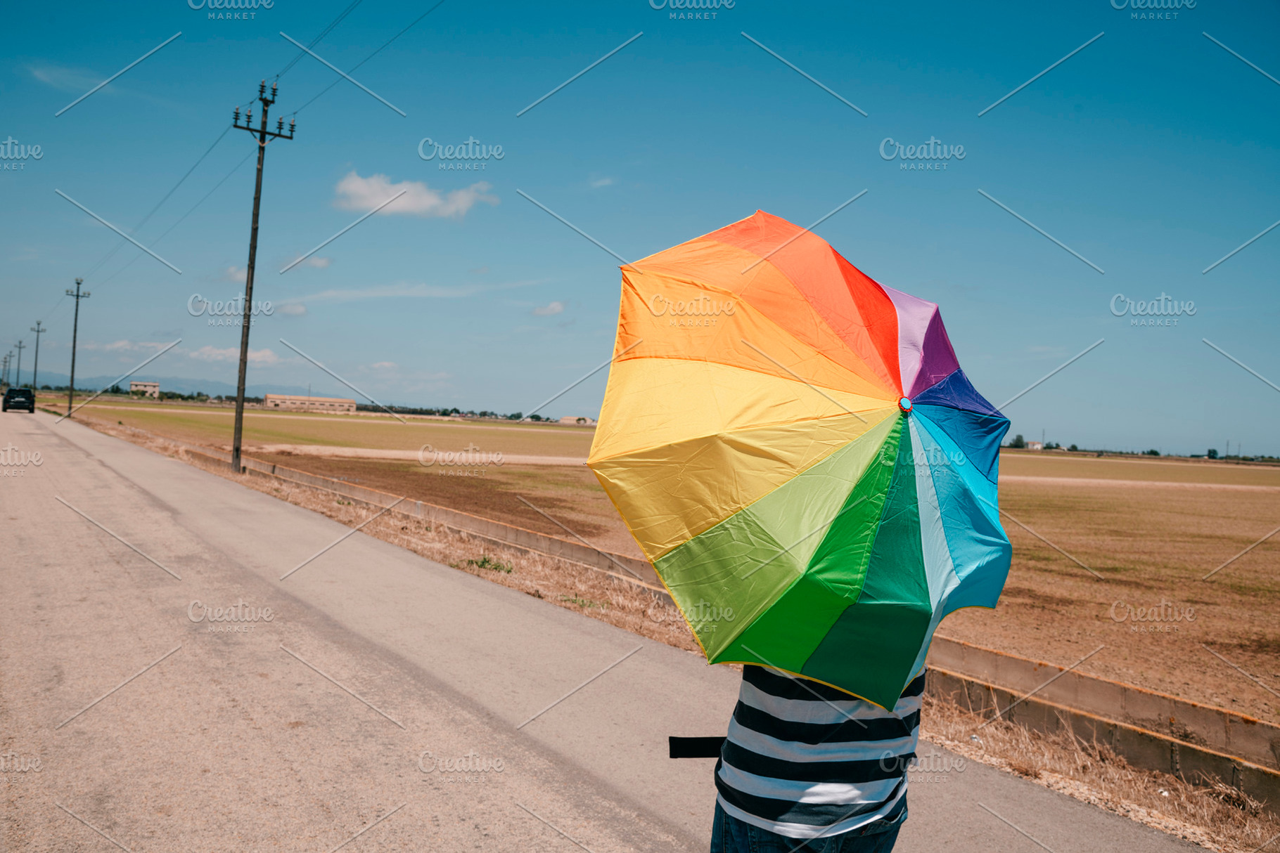 man carrying a rainbow umbrella on his shoulders, a Photo by Nito