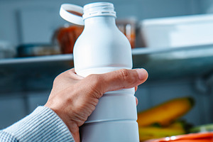 a man reaches for drinkable yogurt in open fridge, a Photo by Nito
