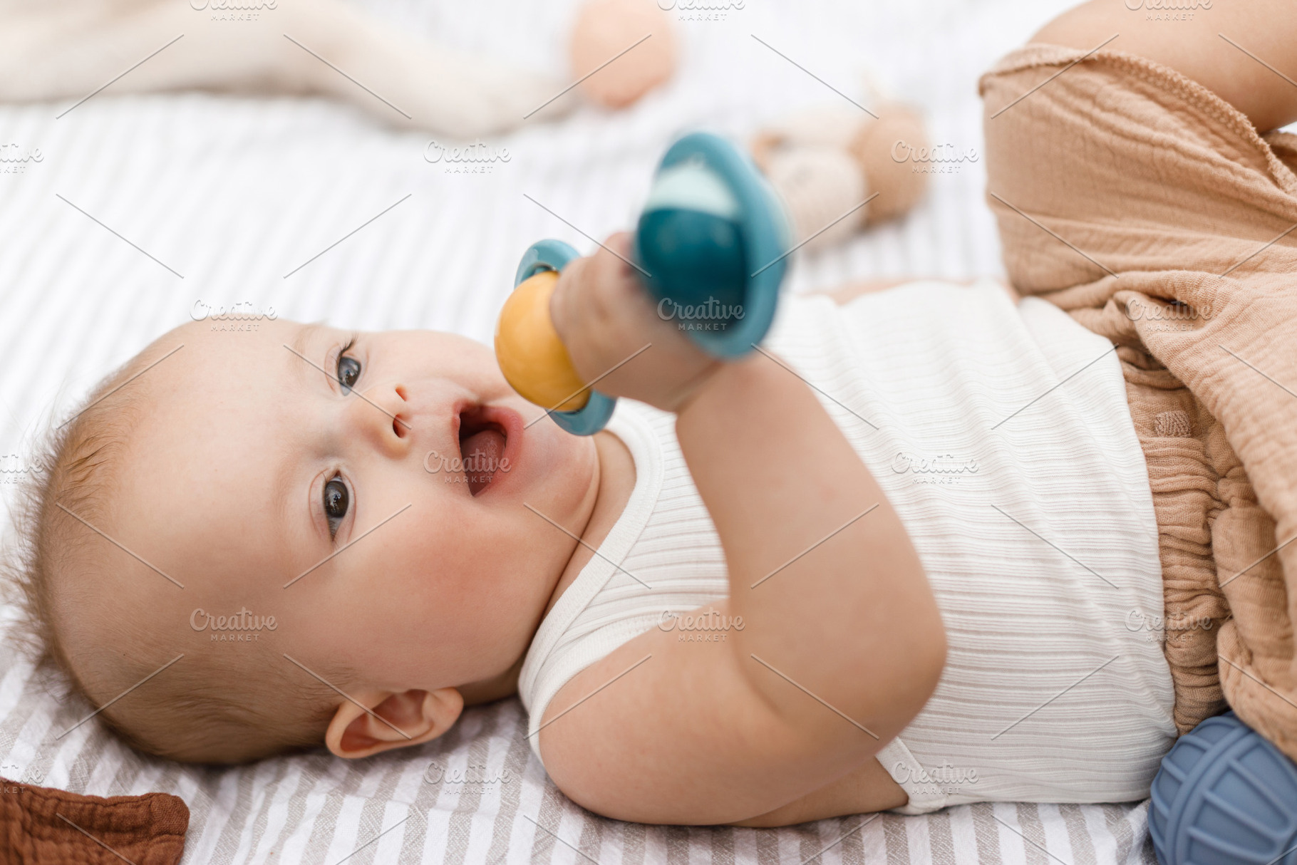Beautiful happy baby lying on blanket and playing with toys on b, a Person Photo by Sonjachni