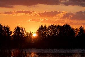 a lake with water colored in the color of sunset in the summer season, a Photo by rsoollAI