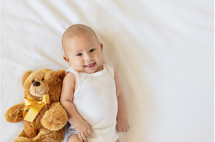 Baby plays with teddy bear against