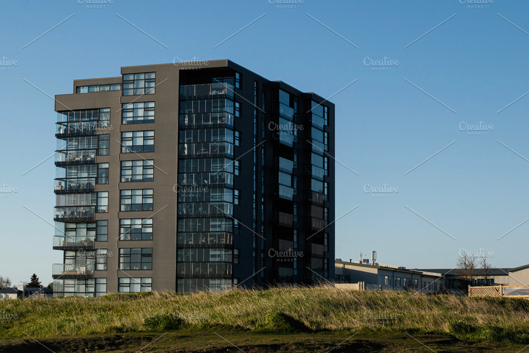 Modern multistory apartment building in Akranes, Iceland during a sunny day, a Photo by AS photostudio