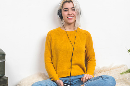 Woman listening to music with headphones, sitting on a rug., a Person Photo by RF Images