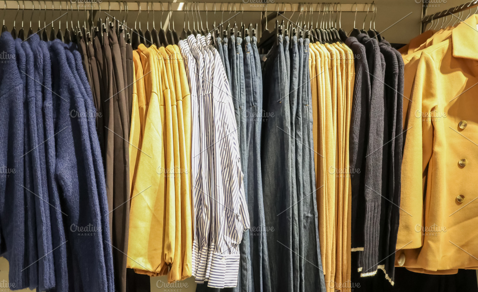Clothing selection hanging on display racks in a retail store, showing various, a Photo by Studio ANNA