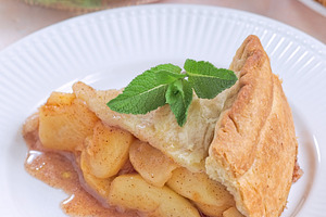 Old fashioned deep dish peach pie slice garnished with fresh mint, on white pla, a Food & Drink Photo by iuliia_n